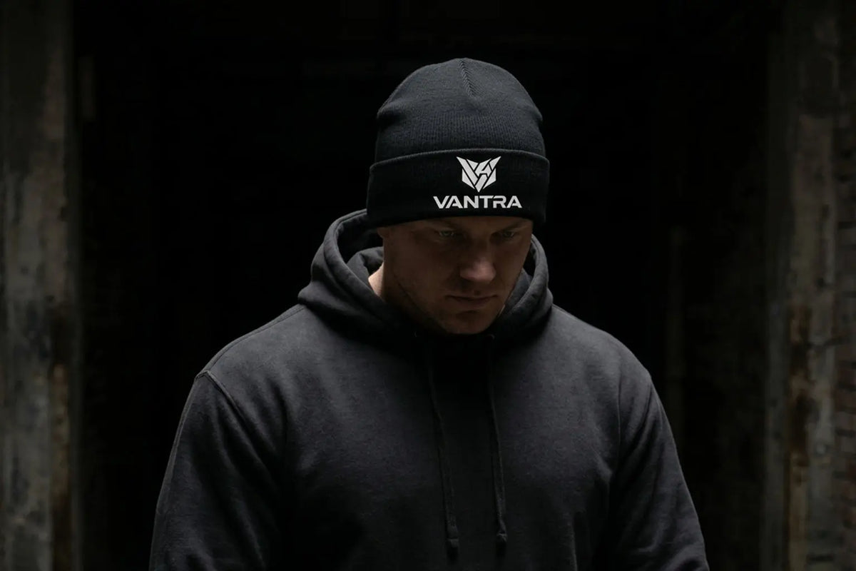BEANIE STREET COLD VANTRA
Homme portant le bonnet noir à revers VANTRA et un sweat à capuche foncé, style streetwear d'hiver et urbain.
