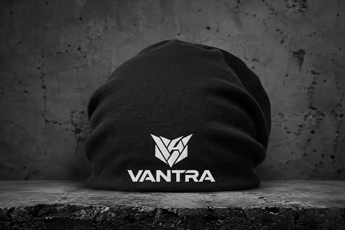 VANTRA LOW KEY VANTRA
Bonnet long en jersey noir souple sans revers avec logo blanc VANTRA, posé sur un fond en béton urbain.