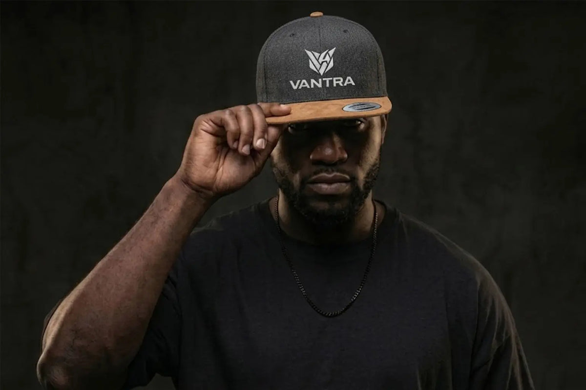 Homme portant la casquette snapback grise et marron VANTRA avec un t-shirt noir, style streetwear premium.