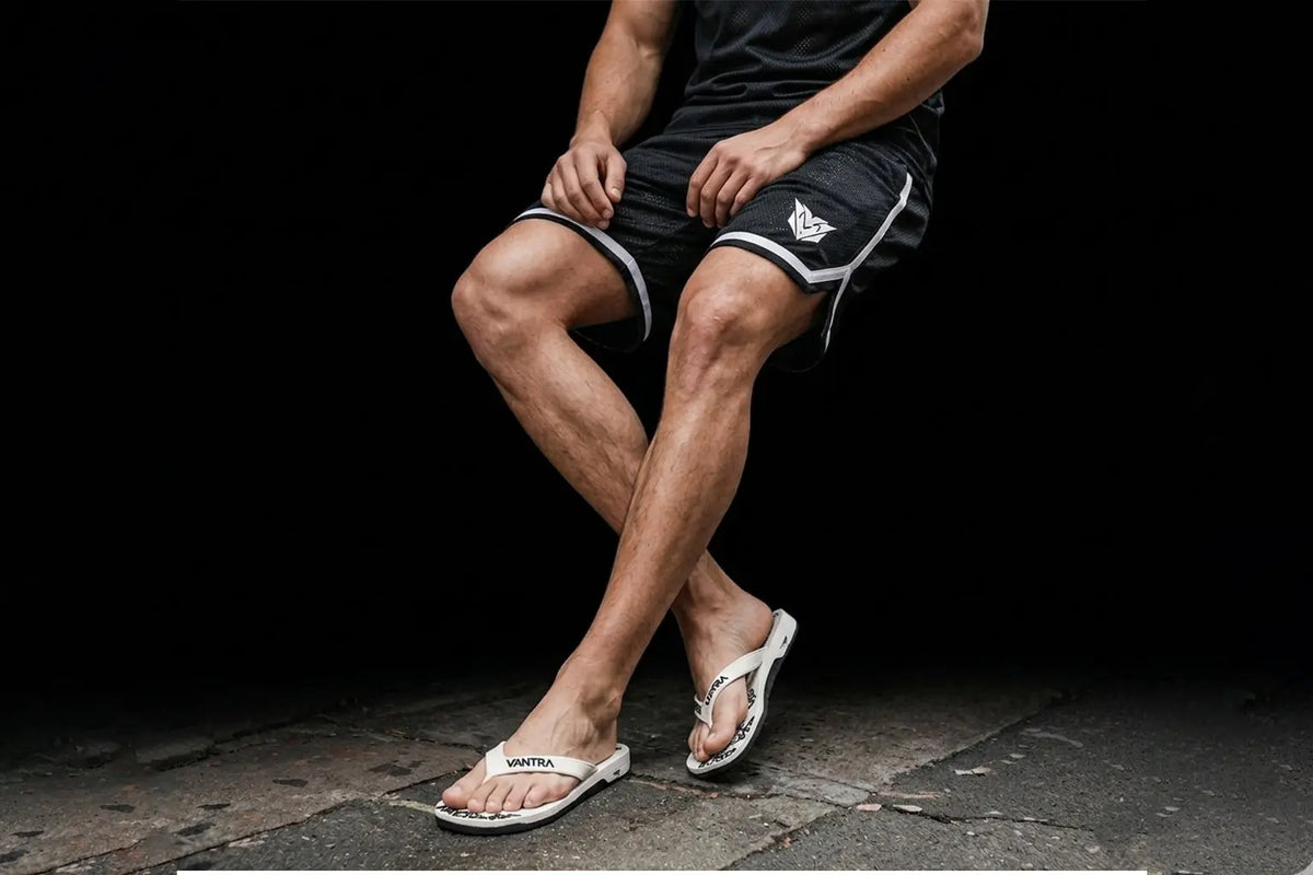 Short de sport en polyester noir VANTRA avec liseré blanc et logo blanc brodé sur la cuisse, porté de face.