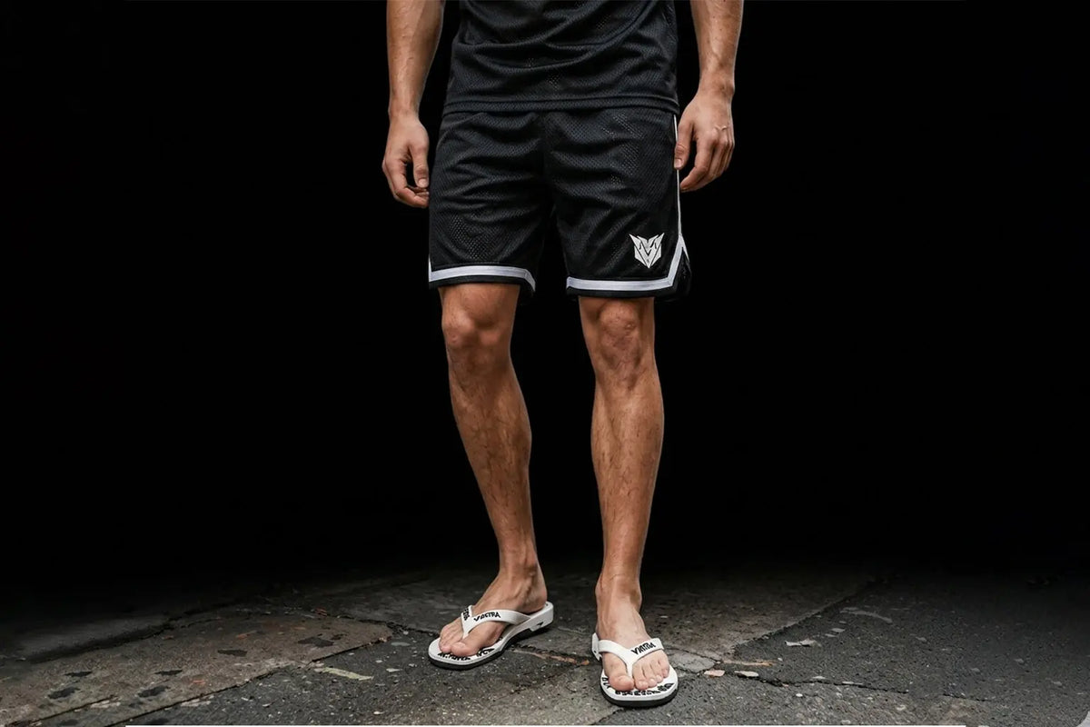 Short de sport en polyester noir VANTRA avec liseré blanc et logo blanc brodé sur la cuisse, porté de face.