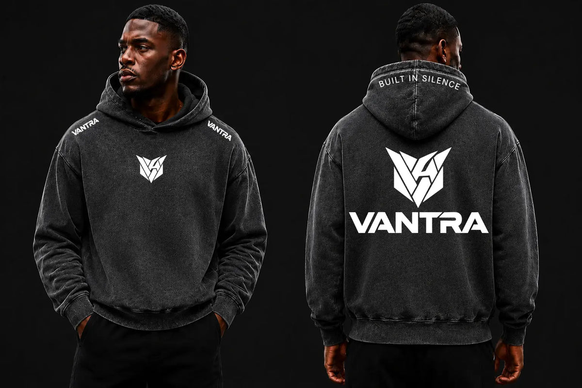 Duo de mannequins portant le sweat à capuche délavé VANTRA, mettant en valeur le design avant épuré et le grand marquage blanc géométrique à l'arrière sur fond sombre.
